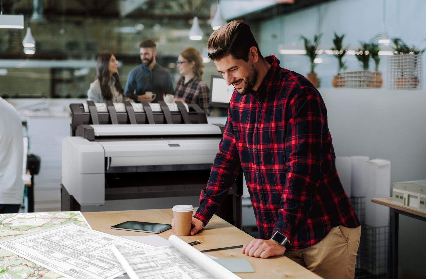 Architect reviewing drawings beside an HP DesignJet T2600 multifunction plotter